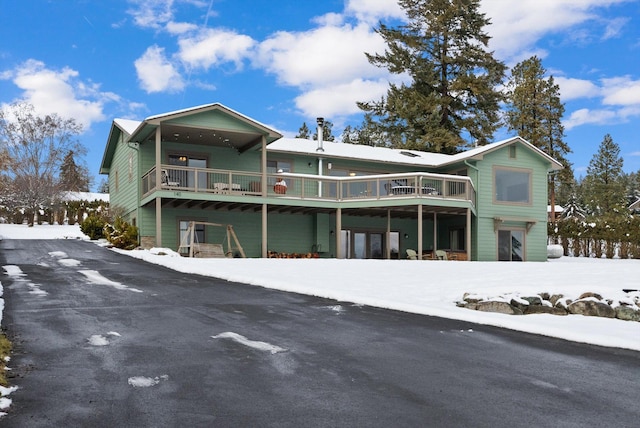 snow covered rear of property featuring a deck