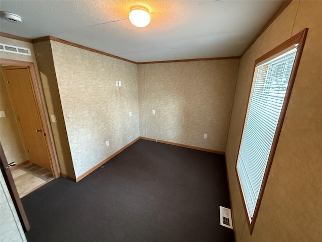 unfurnished room featuring a textured ceiling, ornamental molding, and carpet floors