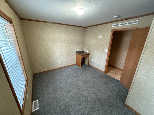 unfurnished bedroom featuring carpet, a textured ceiling, and ornamental molding