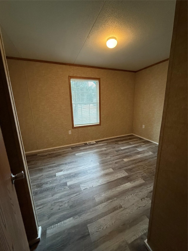 spare room with wood-type flooring, a textured ceiling, and ornamental molding