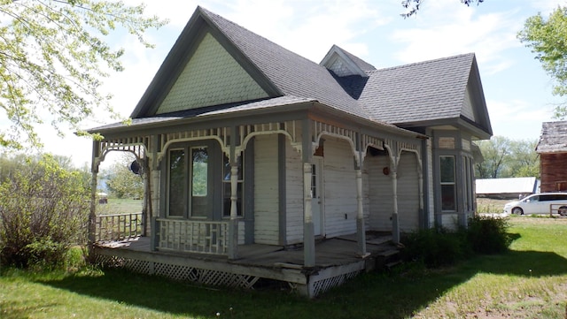 rear view of house featuring a lawn and a porch