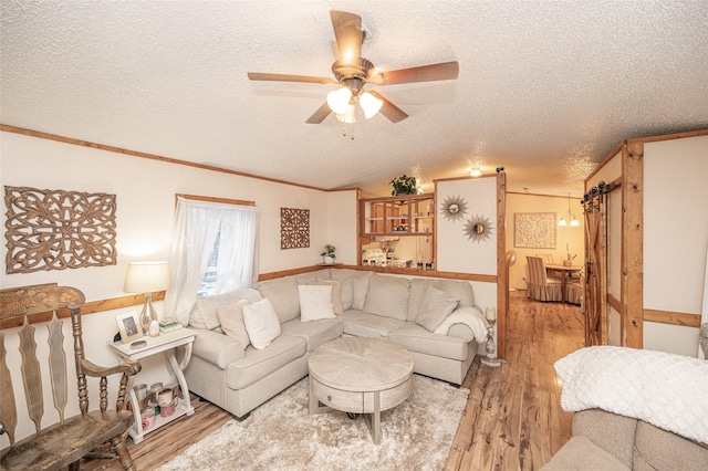 living room with lofted ceiling, light hardwood / wood-style flooring, ceiling fan, and a textured ceiling