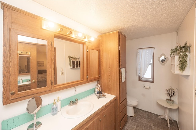 bathroom featuring vanity, a textured ceiling, and toilet