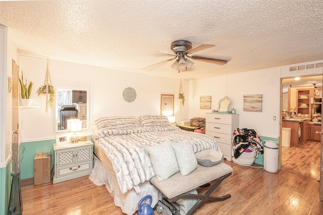 bedroom featuring ceiling fan, a textured ceiling, and light hardwood / wood-style flooring