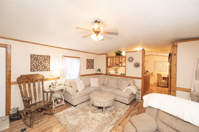 living room featuring a textured ceiling, light hardwood / wood-style flooring, ceiling fan, and ornamental molding