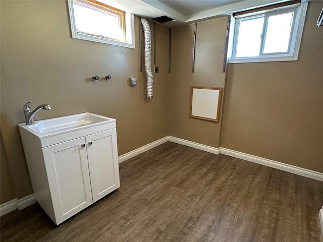 clothes washing area featuring dark wood-type flooring, sink, and cabinets