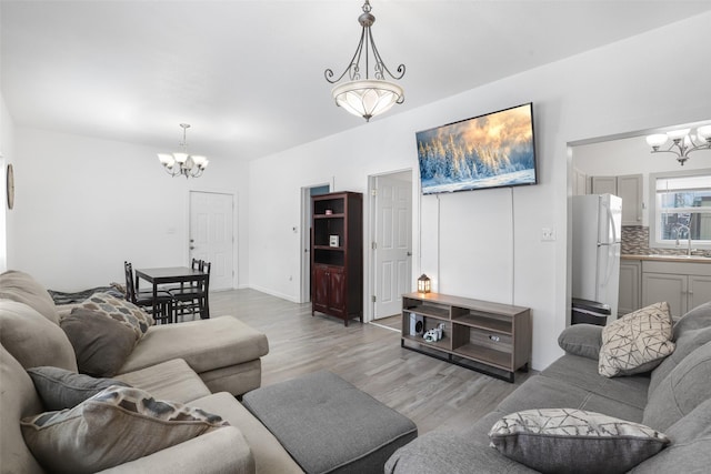 living room with hardwood / wood-style flooring, a notable chandelier, and sink