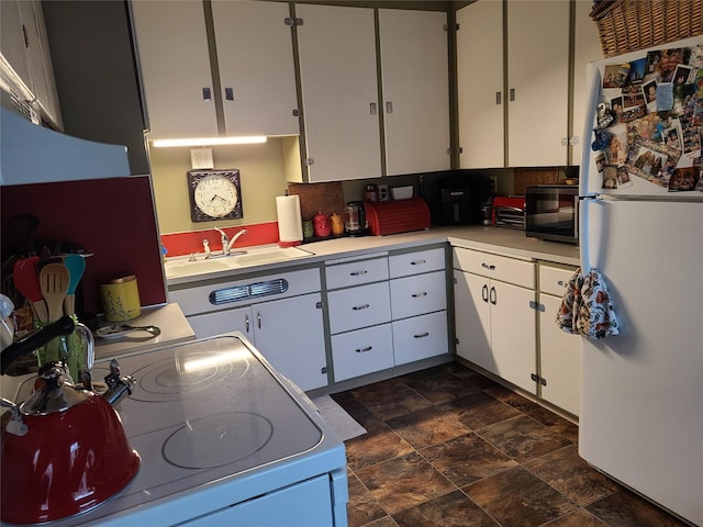 kitchen featuring range, white refrigerator, and white cabinetry