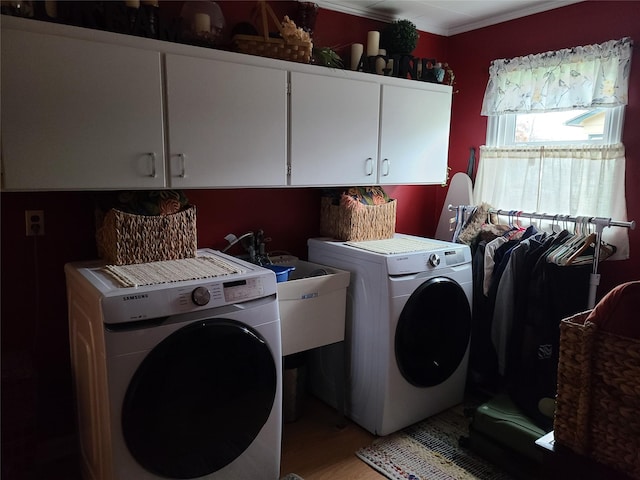 clothes washing area featuring washing machine and clothes dryer, sink, cabinets, light hardwood / wood-style flooring, and ornamental molding