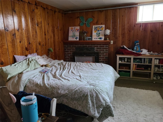 bedroom with carpet floors, a brick fireplace, and wood walls