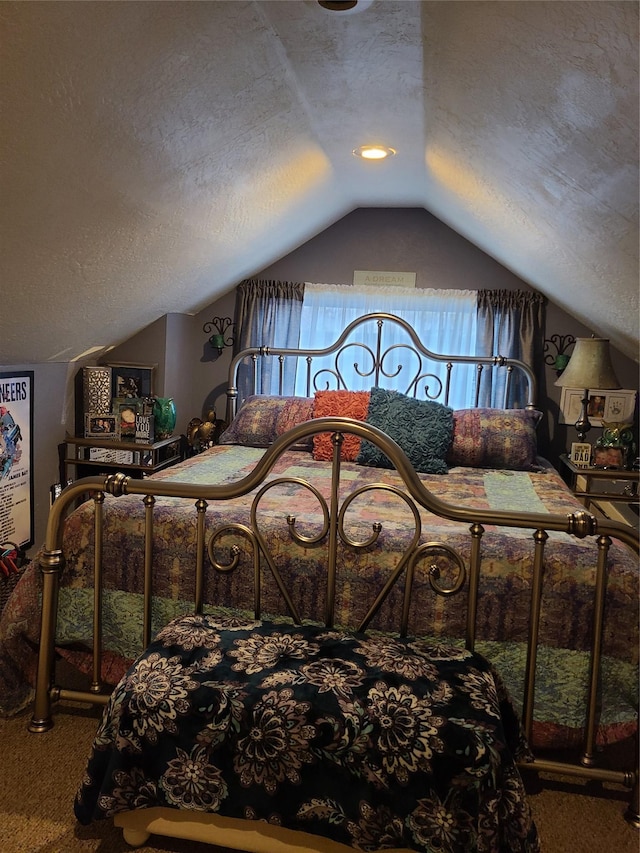 carpeted bedroom with a textured ceiling and vaulted ceiling