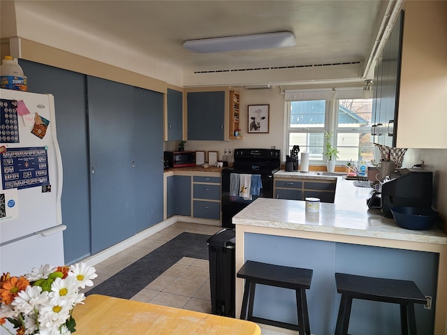 kitchen with black range with electric cooktop, white refrigerator, kitchen peninsula, a breakfast bar, and light tile patterned floors