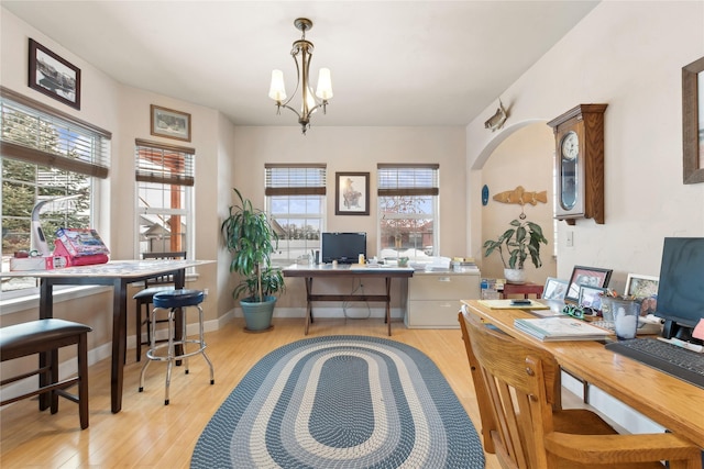 office with light wood-type flooring and a chandelier