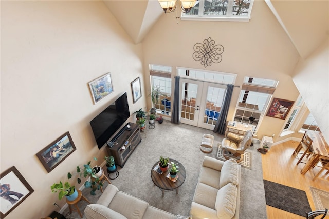 living room featuring a notable chandelier, wood-type flooring, a high ceiling, and french doors