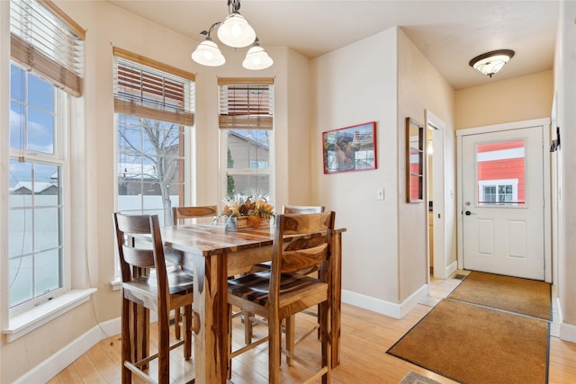 dining space featuring a healthy amount of sunlight, light hardwood / wood-style floors, and an inviting chandelier