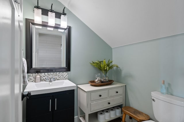 bathroom featuring tasteful backsplash, vanity, vaulted ceiling, and toilet