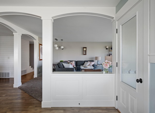 interior space featuring decorative columns and dark hardwood / wood-style floors