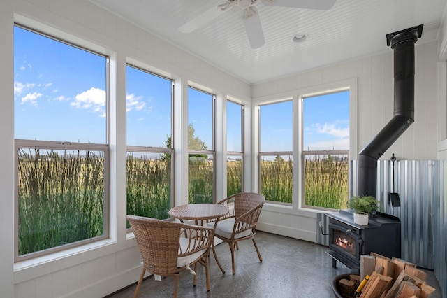 sunroom featuring a wood stove and ceiling fan