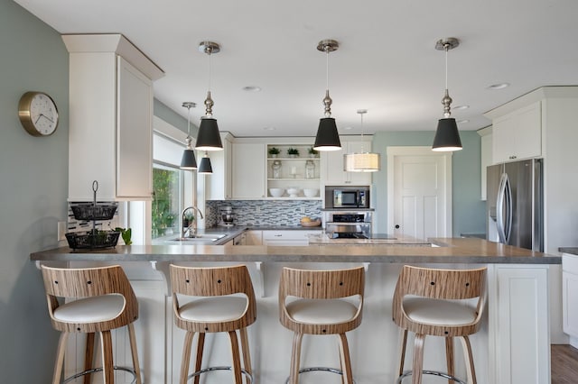 kitchen with white cabinetry, built in microwave, sink, hanging light fixtures, and stainless steel refrigerator with ice dispenser