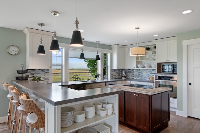 kitchen with kitchen peninsula, white cabinetry, oven, and hanging light fixtures