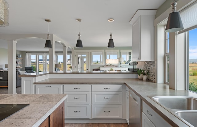 kitchen featuring decorative columns, a wealth of natural light, white cabinetry, and black electric stovetop