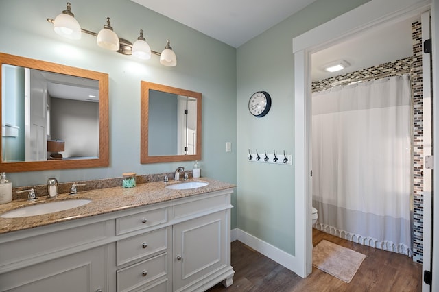 bathroom with wood-type flooring, vanity, toilet, and curtained shower