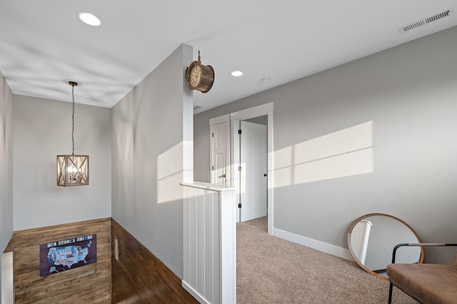 hall featuring a chandelier and dark carpet