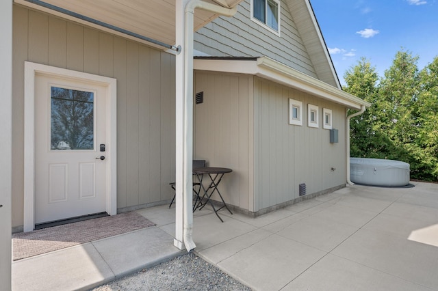 entrance to property with a hot tub and a patio area