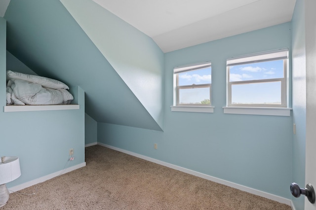 bonus room with lofted ceiling and light carpet