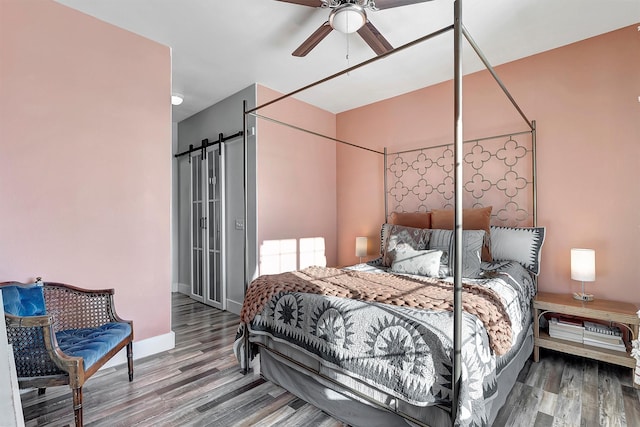 bedroom featuring a barn door, ceiling fan, and hardwood / wood-style flooring