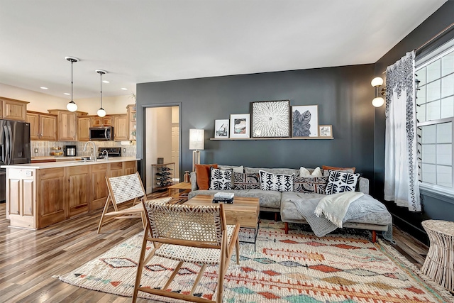 living room with a wealth of natural light, sink, and light hardwood / wood-style floors