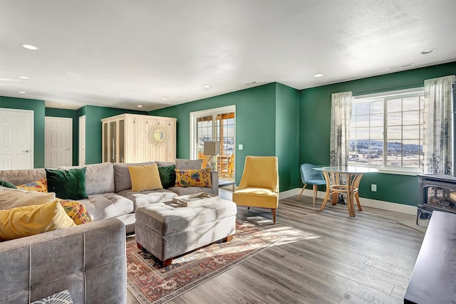 living room with wood-type flooring, a wealth of natural light, and a wood stove