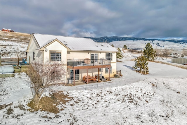 snow covered property featuring a deck with mountain view