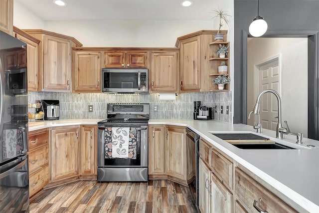 kitchen with decorative backsplash, appliances with stainless steel finishes, sink, wood-type flooring, and pendant lighting