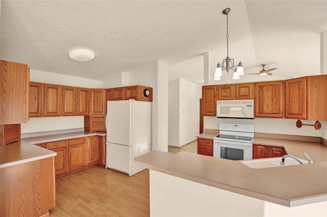 kitchen with kitchen peninsula, white appliances, hanging light fixtures, and lofted ceiling