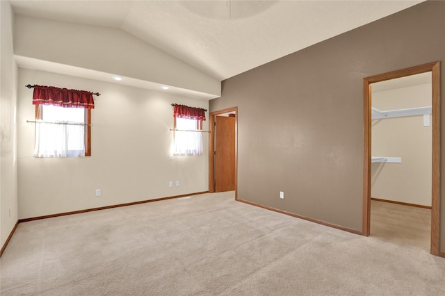 empty room with light colored carpet and vaulted ceiling