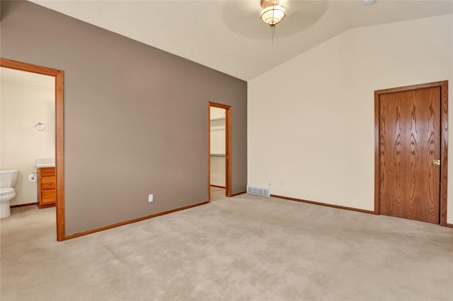 unfurnished bedroom featuring lofted ceiling, light carpet, ensuite bath, ceiling fan, and a closet