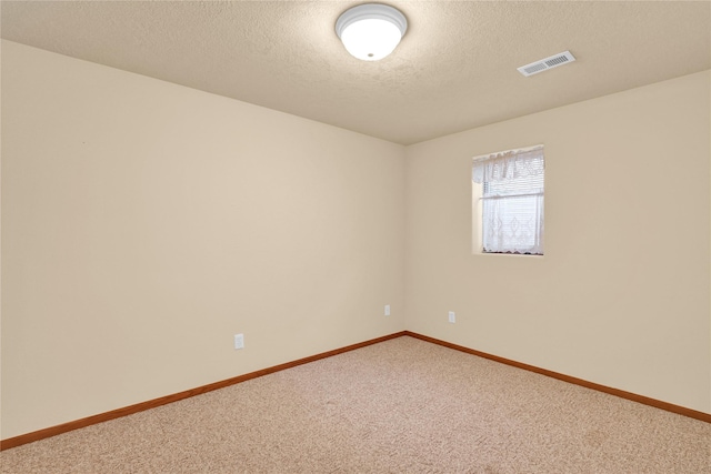 carpeted empty room with a textured ceiling