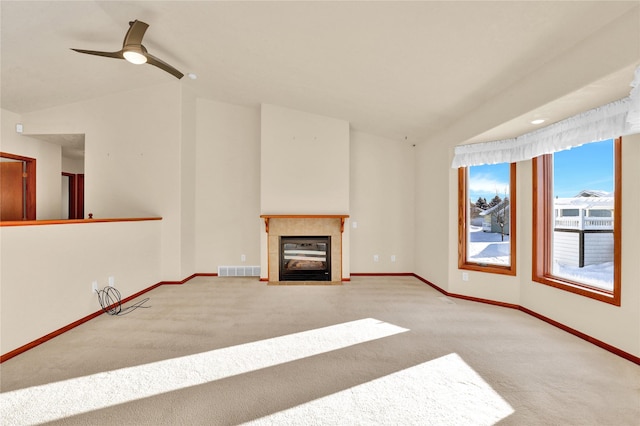 unfurnished living room featuring carpet flooring, ceiling fan, vaulted ceiling, and a tiled fireplace