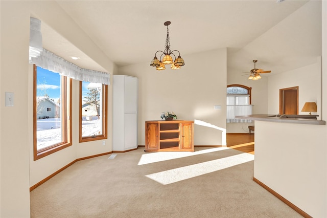 unfurnished room with ceiling fan with notable chandelier, light colored carpet, and vaulted ceiling