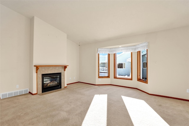 unfurnished living room with light colored carpet and a tiled fireplace