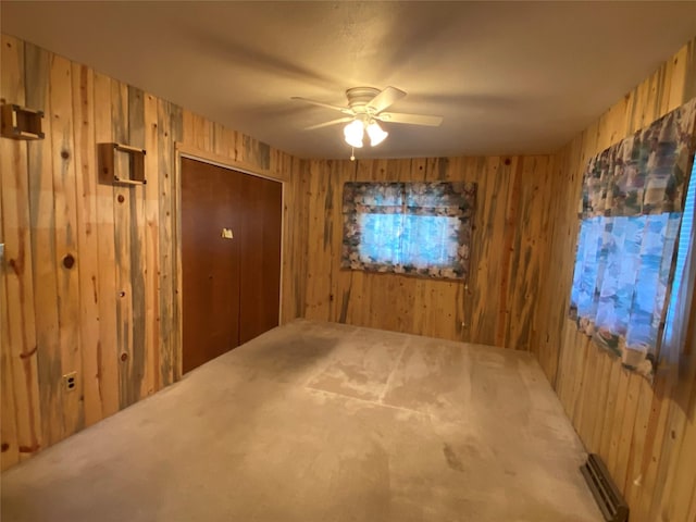 spare room with carpet flooring, ceiling fan, and wood walls