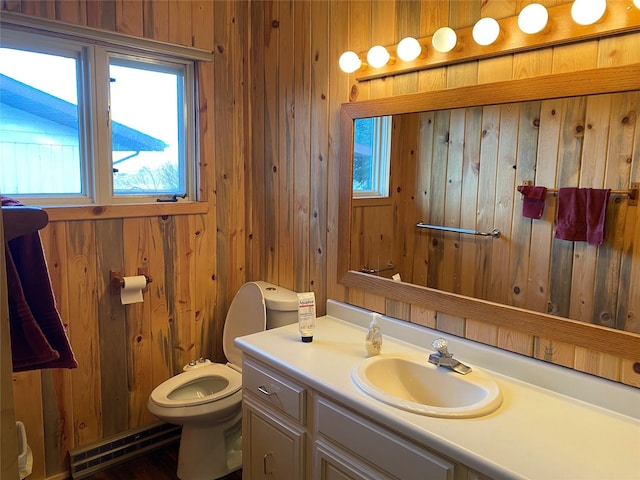 bathroom with wood walls, vanity, toilet, and a baseboard heating unit