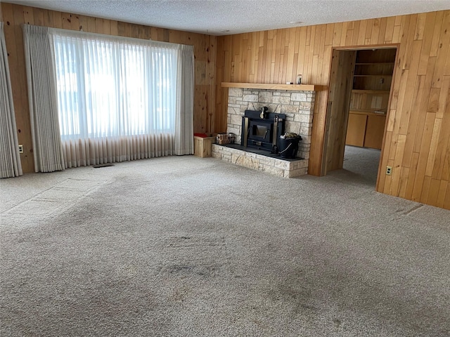 unfurnished living room with carpet floors, wooden walls, and a textured ceiling