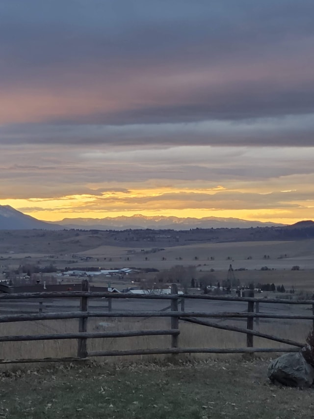 yard at dusk featuring a mountain view and a rural view