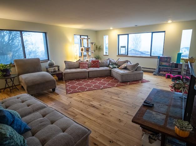 living room featuring a healthy amount of sunlight, wood-type flooring, and a baseboard heating unit