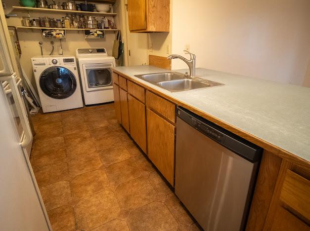 kitchen with white refrigerator, separate washer and dryer, stainless steel dishwasher, and sink