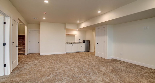 unfurnished living room with light carpet and sink