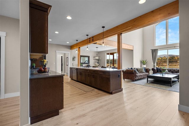 kitchen with a kitchen island with sink, sink, hanging light fixtures, dark brown cabinets, and beam ceiling