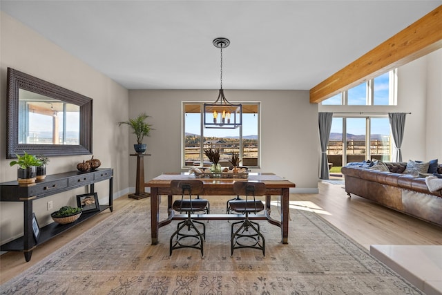 dining room featuring beam ceiling, a mountain view, light hardwood / wood-style flooring, and a chandelier